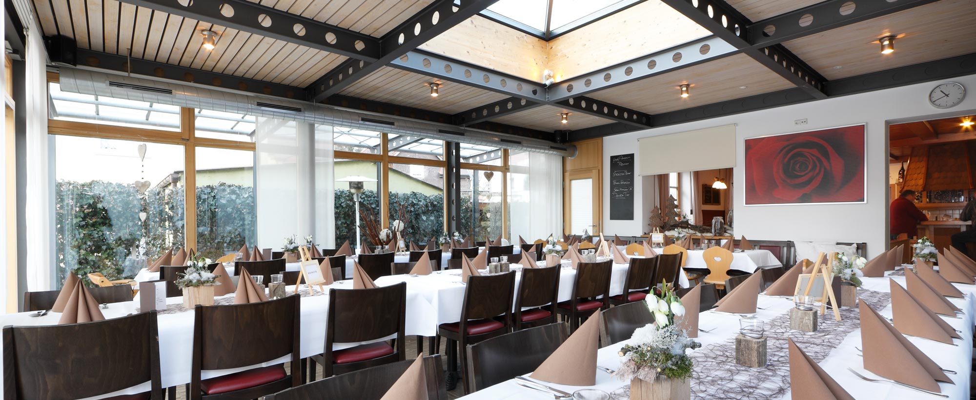 Blick in den Wintergarten im Gasthaus Rosengarten in Bad Buchau über gedeckte Tische hinweg.